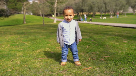 Little-mixed-race-boy-in-park-playing,-running-from-camera